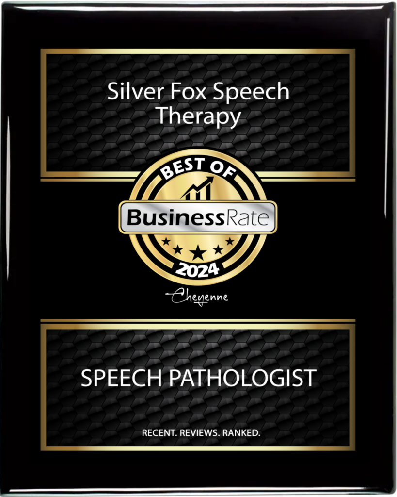 A framed black award plaque with gold accents. It features two rectangular sections. The top section reads "Silver Fox Speech Therapy" in white text over a black background with a hexagonal pattern. The bottom section reads "SPEECH PATHOLOGIST" in white text, also over a similar background, with the text "RECENT. REVIEWS. RANKED." below it. In the center is a gold circular badge with the text "BEST OF" over a stylized graph icon, and "BusinessRate" in a rectangular white bar, with five stars below. Beneath the gold circle, is the year "2024" and the city "Cheyenne" in a cursive font.